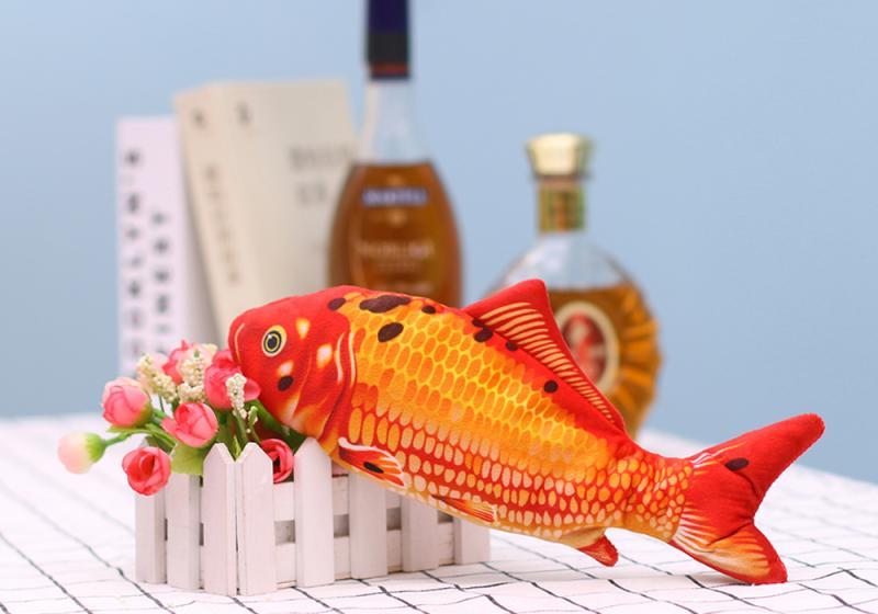 Muezza shoppe interactive fish cat toy in orange with realistic scales resting on white picket fence decor